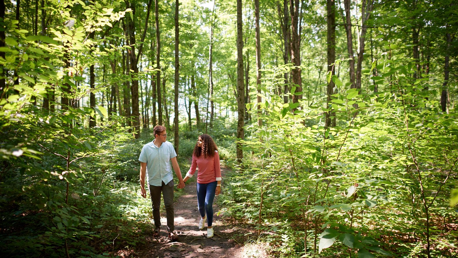 A couple walks in the woods at the Priesthood Restoration Site near Susquehanna Depot, Pennsylvania.
They are surrounded by trees.