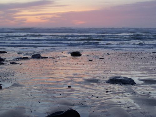 Rocks on the shore and waves in the distance at sunset.