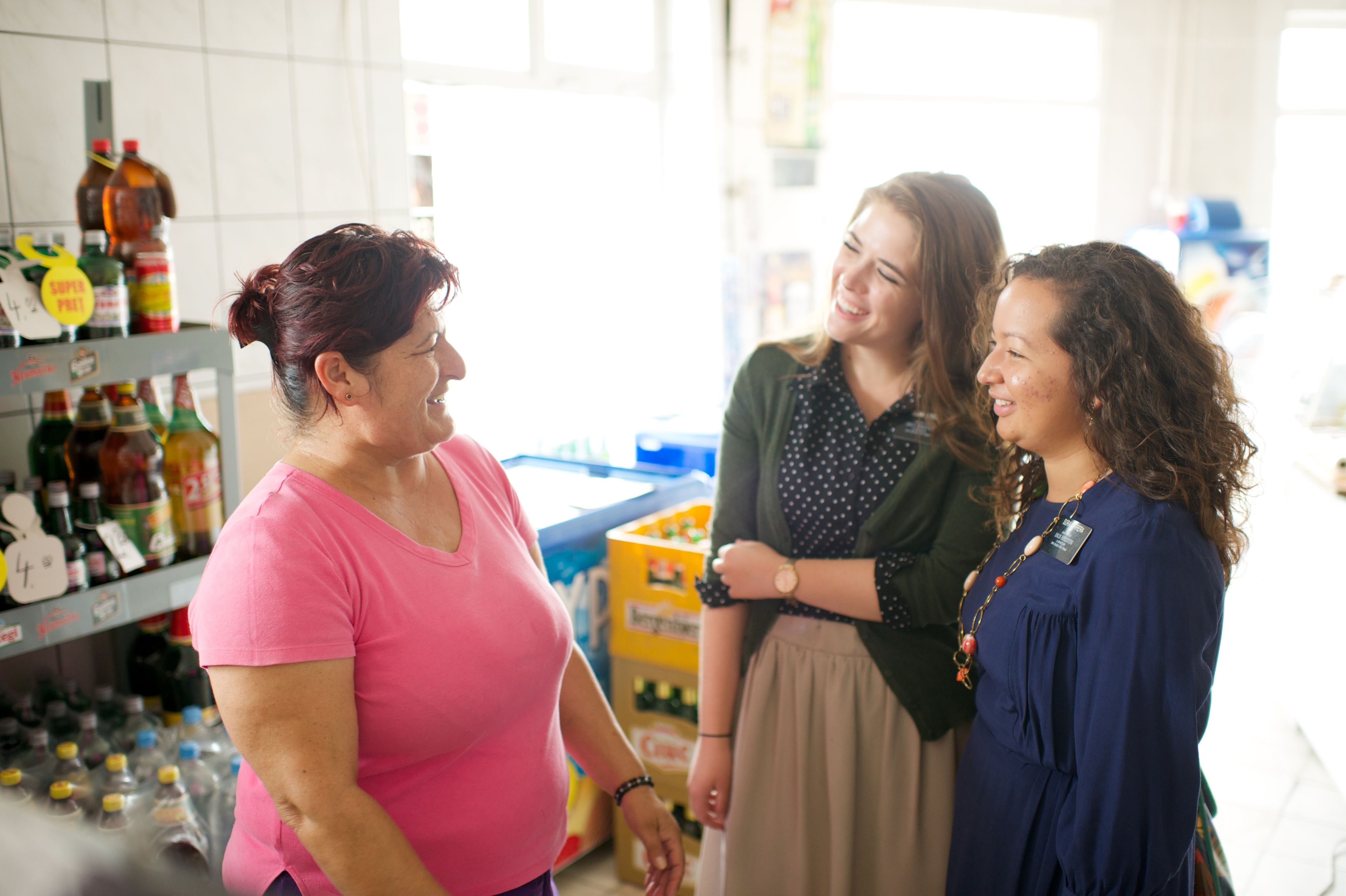 Sister missionaries talking to a woman in a store.