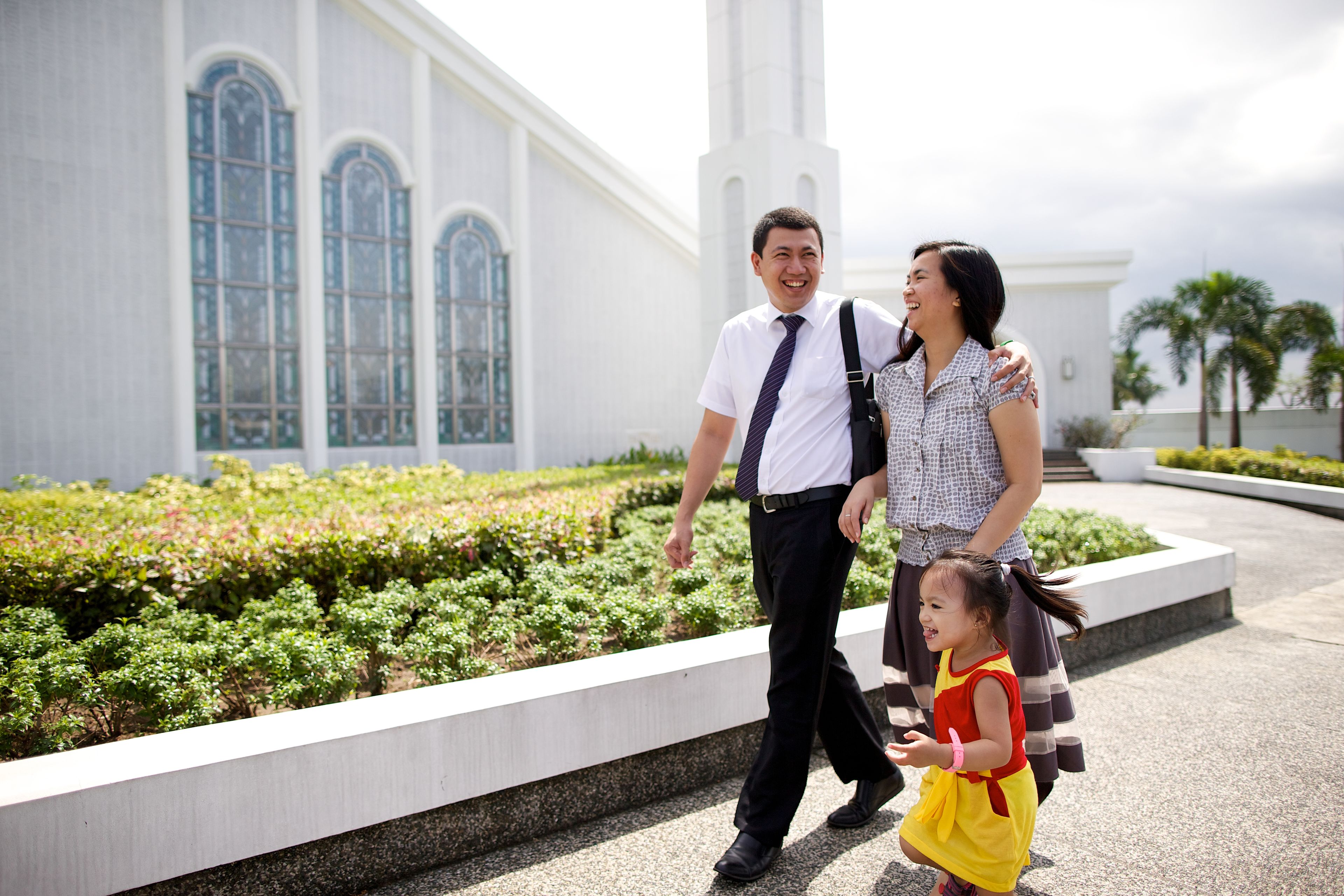 A young couple and their daughter walk outside the Manila Philippines Temple.
