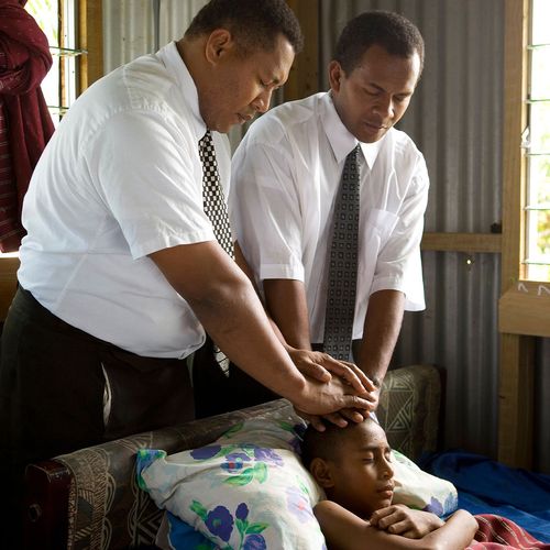 two priesthood holders giving a boy a blessing