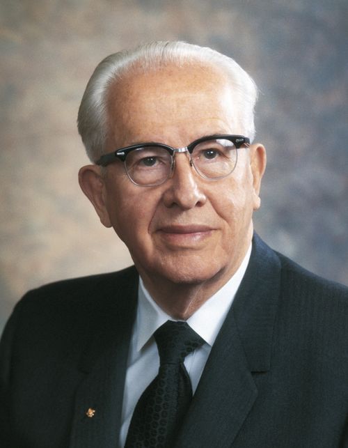 A portrait of President Ezra Taft Benson in a black suit, white shirt, and glasses.