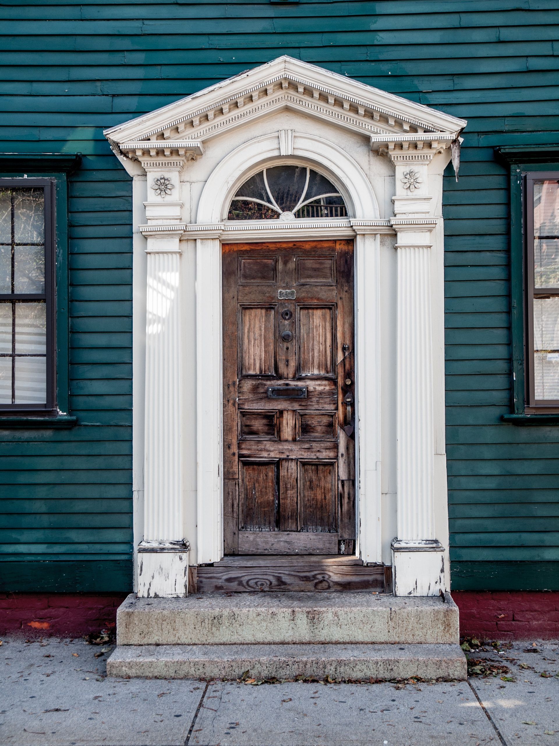 An old wooden door on a teal-colored house.