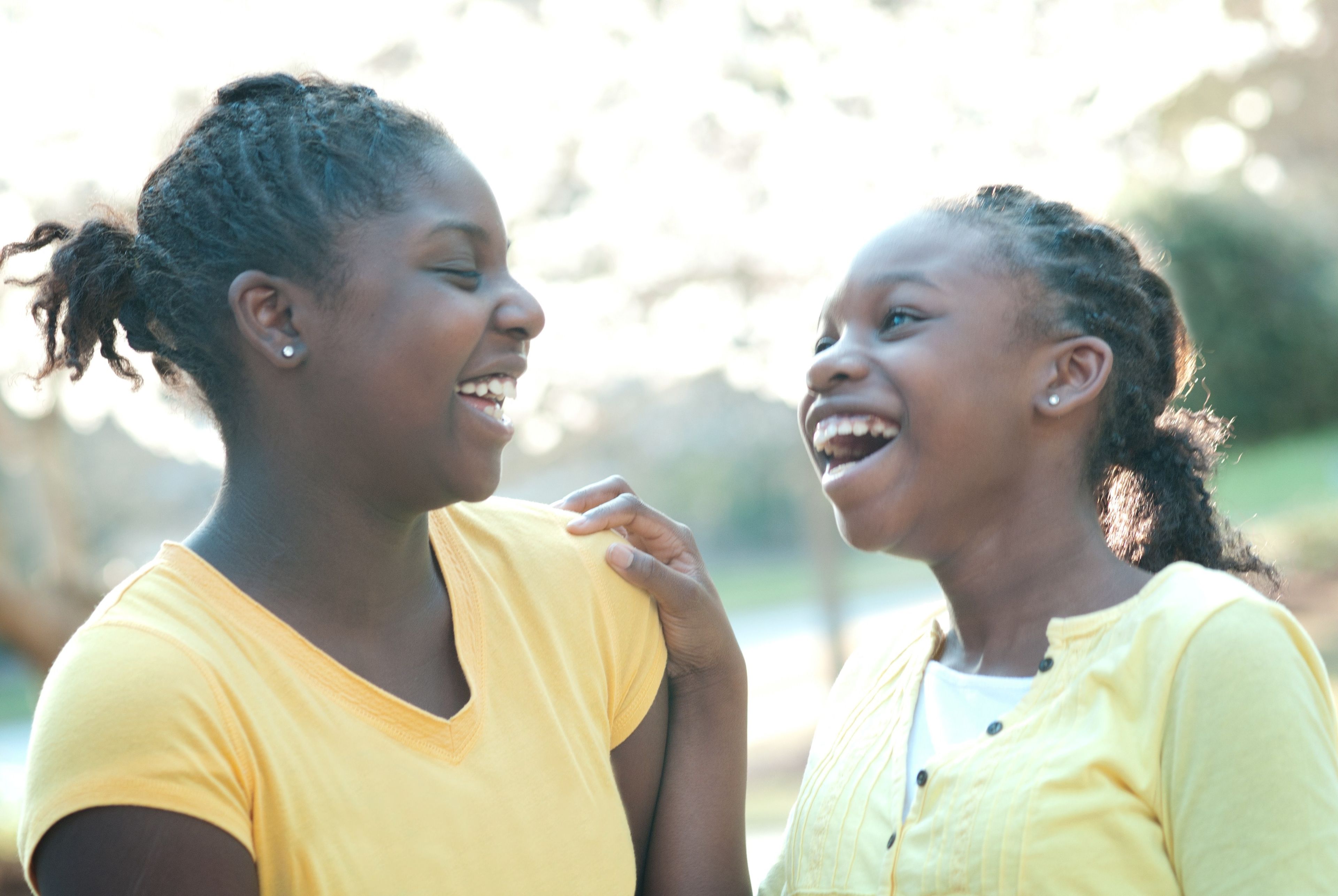 Two young sisters laughing with each other.
