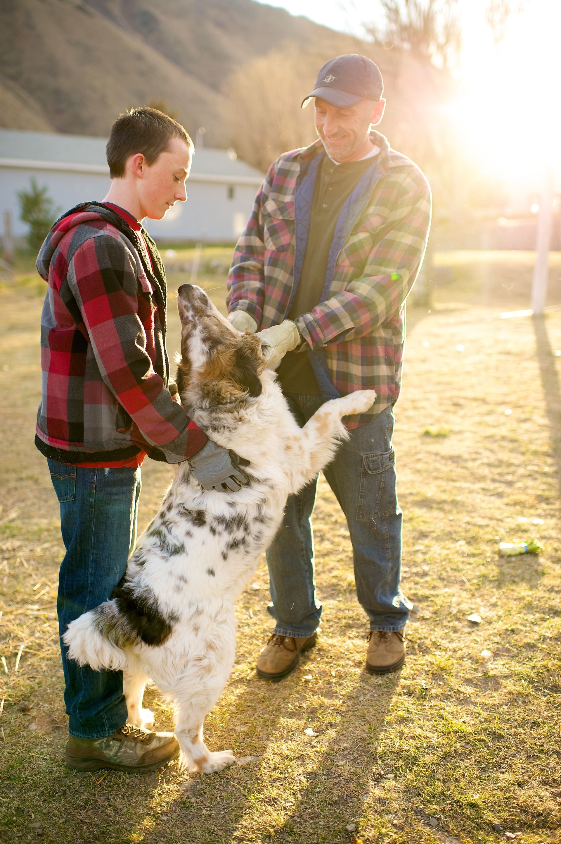 A father and son play with their dog in the yard.