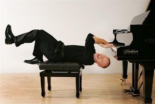 A man playing the piano while lying on his back.