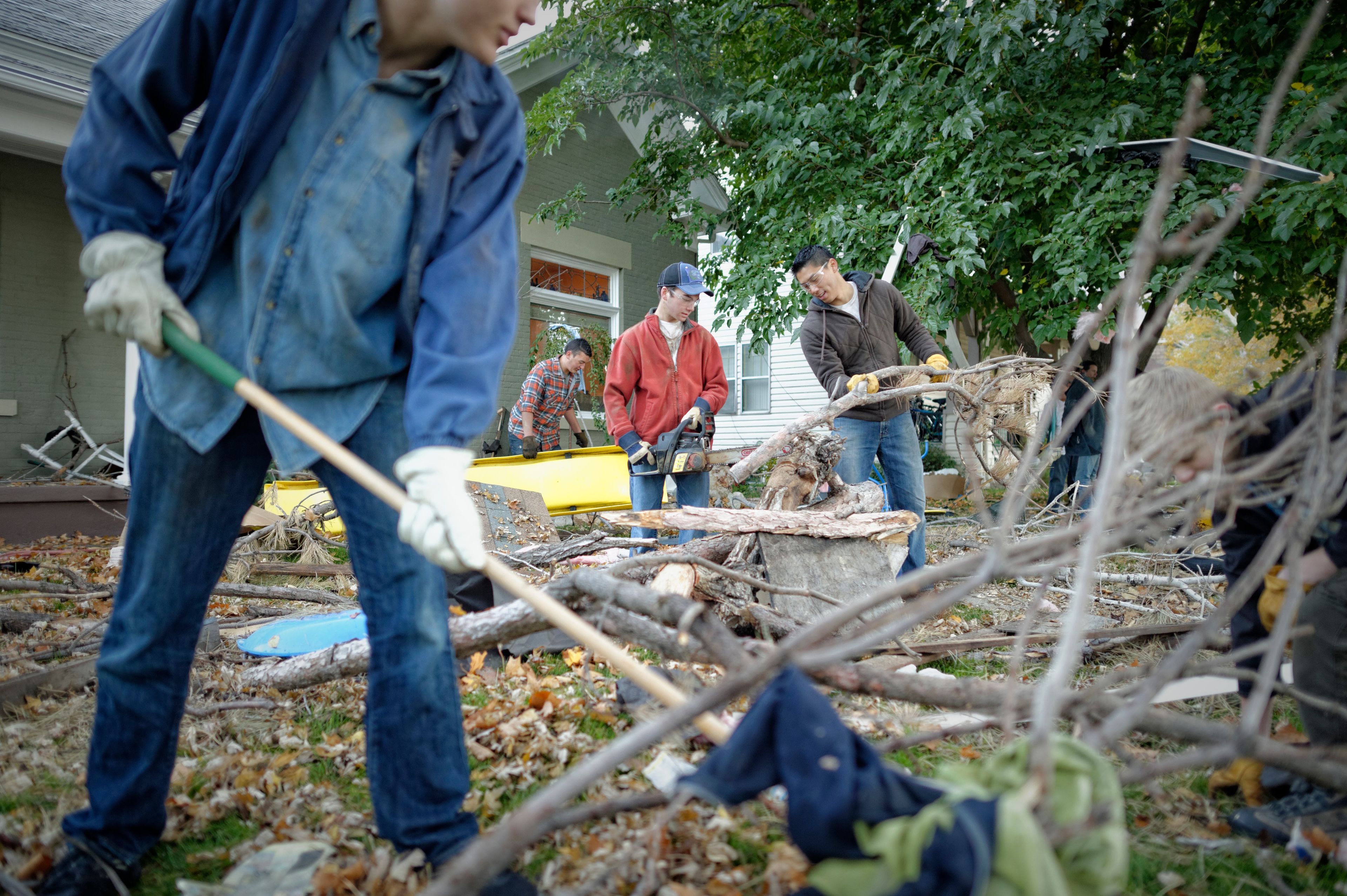 Young men help clean up fallen branches in someone’s yard.  