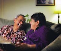 Polynesian couple on a couch with a photo album.