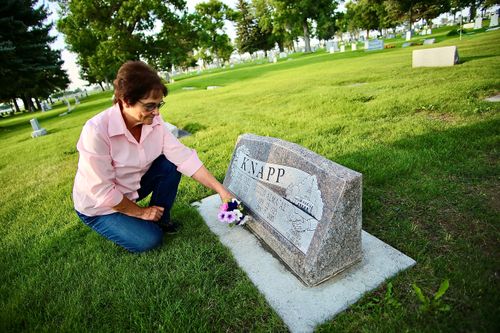 woman putting flowers on gravestone