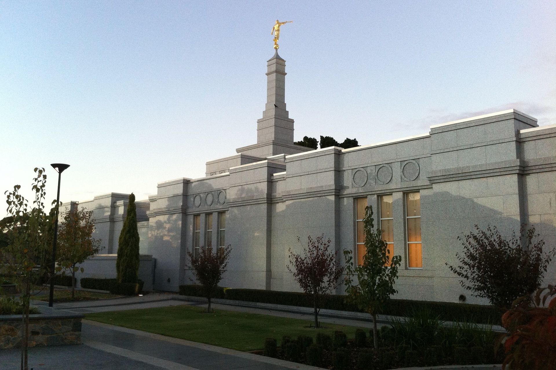 The Perth Australia Temple in the evening, including the spire and exterior of the temple.