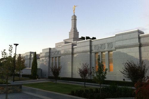 A side view of the Perth Australia Temple in the evening, with small trees growing on the grounds near the building.
