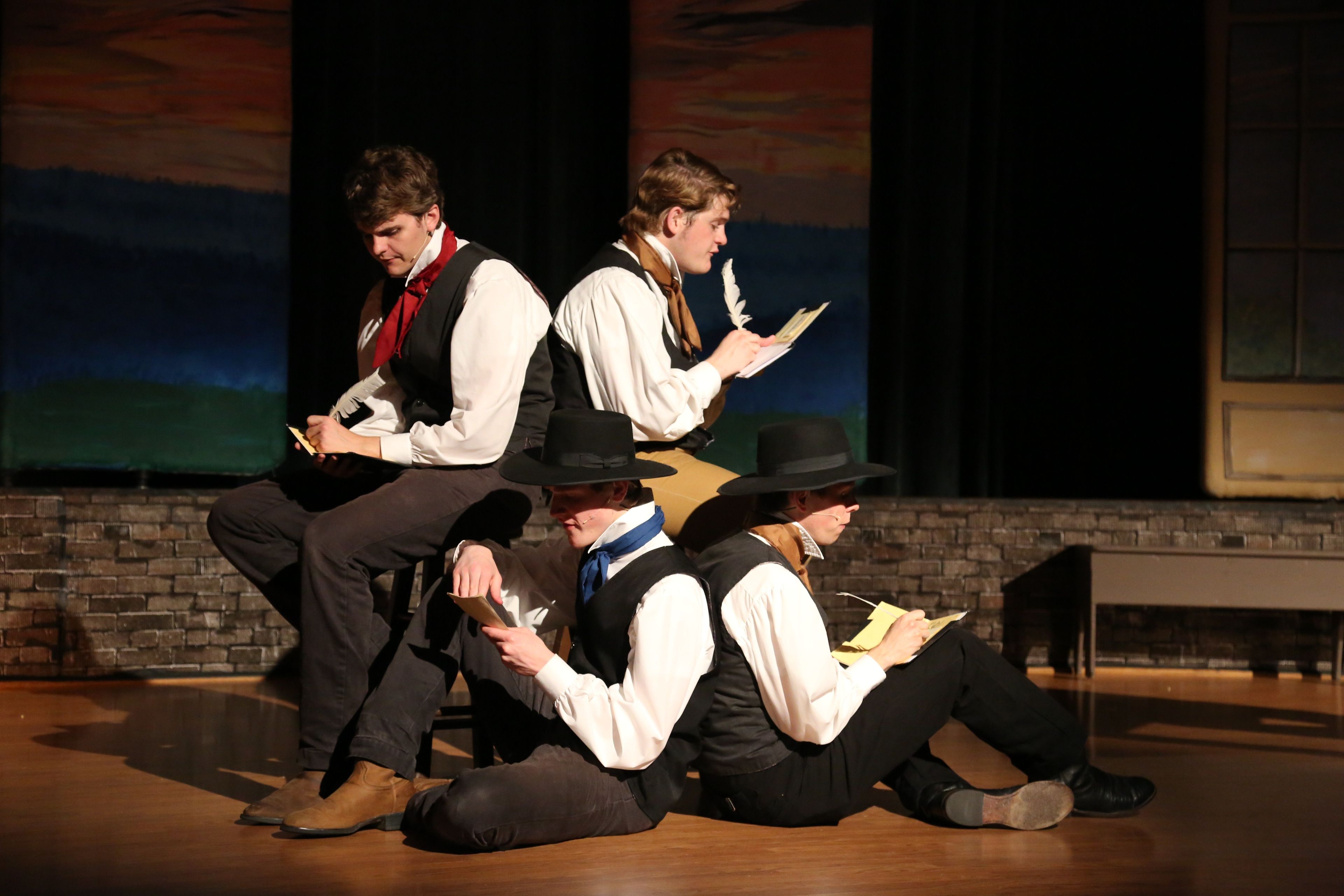 Four actors playing missionaries in the Nauvoo Pageant, writing letters.