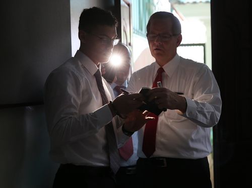 Elder Gary E. Stevenson reading scriptures by light of cell phone