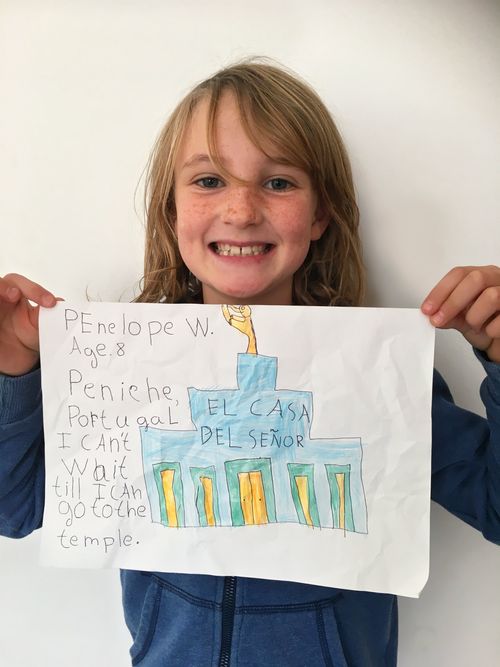 A girl holding up her drawing of the temple