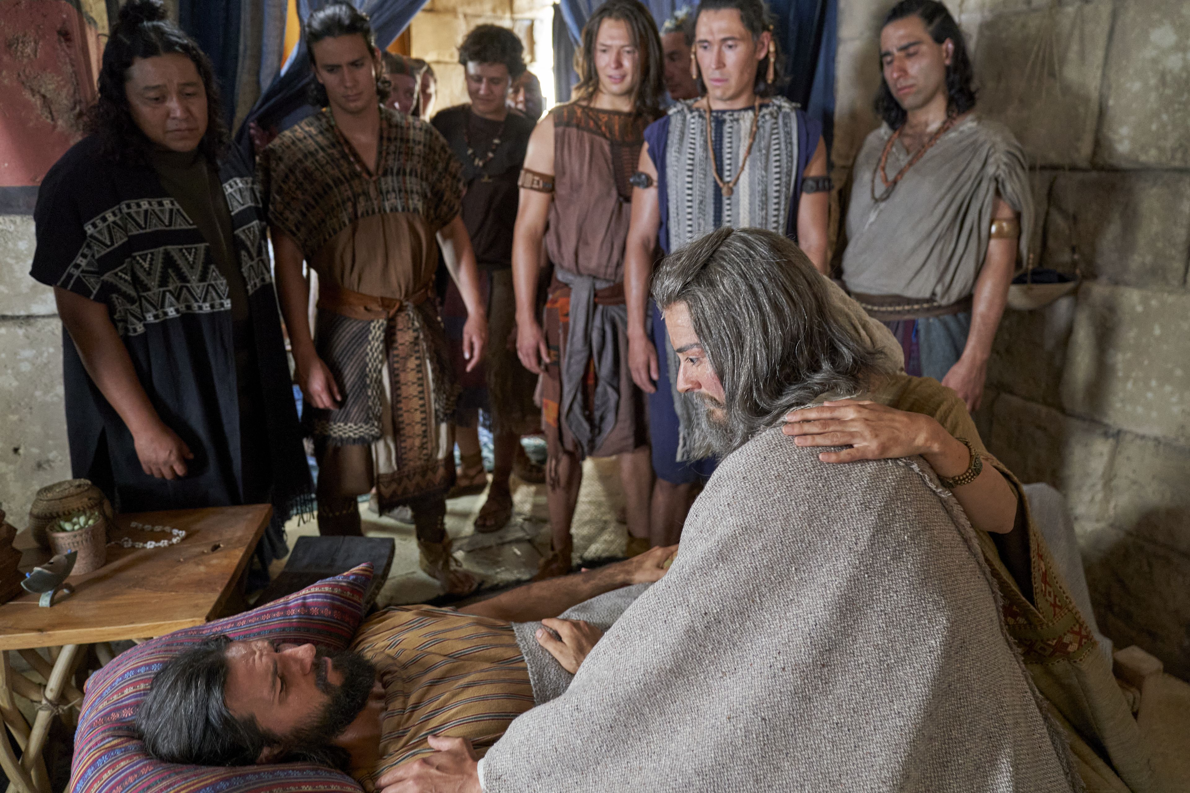 Alma the Younger lays in bed, struck dumb, while his father and the sons of Mosiah look on.