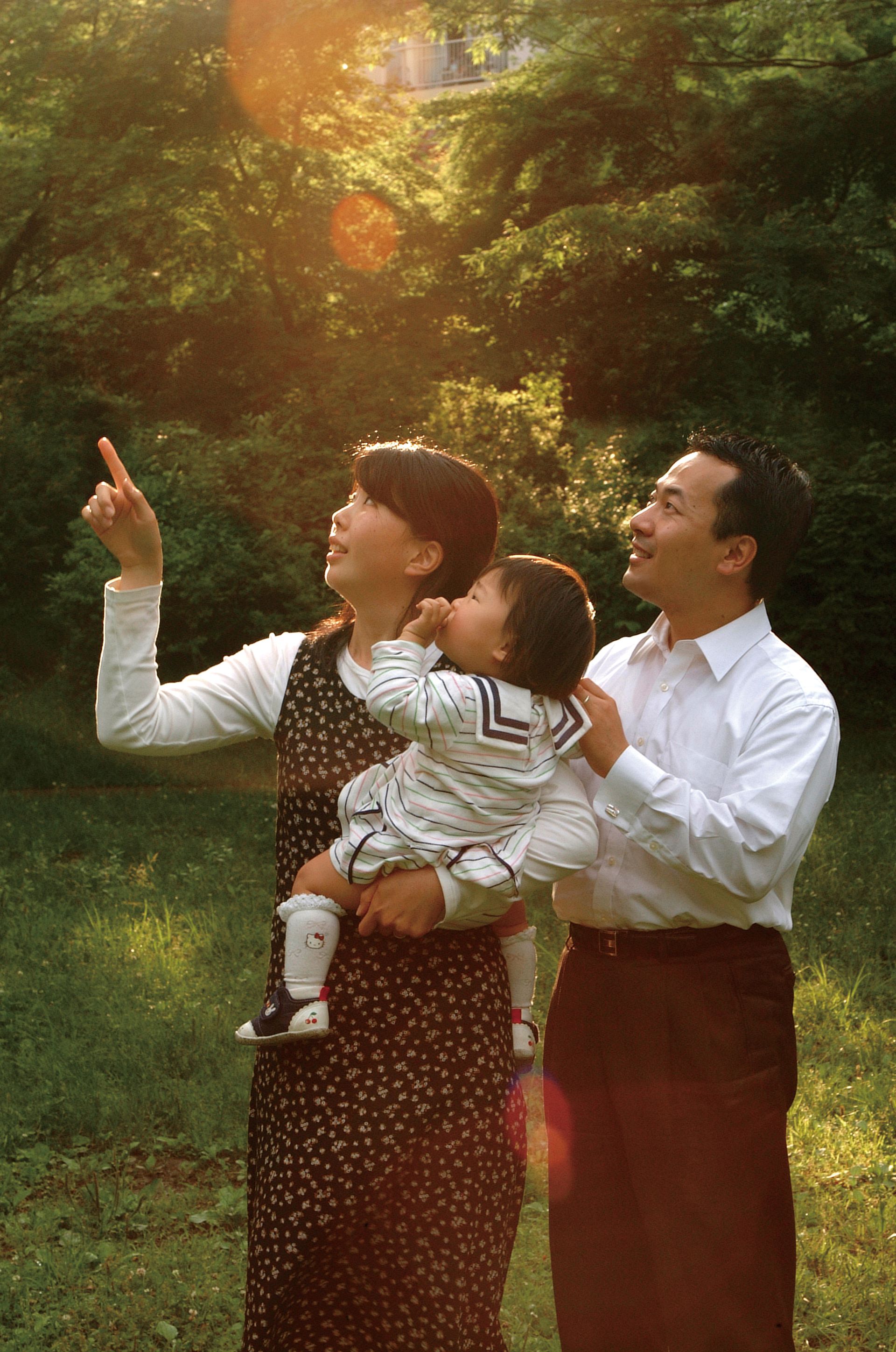 A mother holds her daughter with the father nearby.