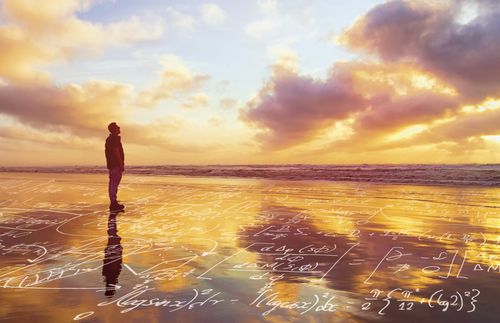 man standing on beach; mathematic symbols appear on the sand