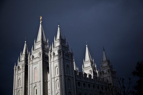 The Salt Lake Temple with a storm overhead. A view of the windows, the angel Moroni, and five of the six spires.
