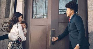 a young man opens a door for a woman and child