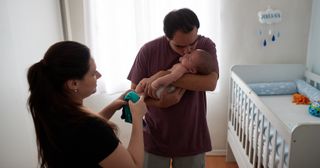 a father and mother dress their baby