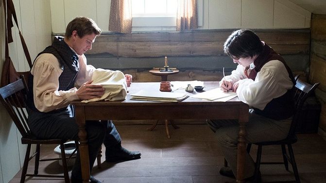 Images from the film "Days of Harmony." Joseph Smith and Oliver Cowdery sit at a table and translate the Book of Mormon.