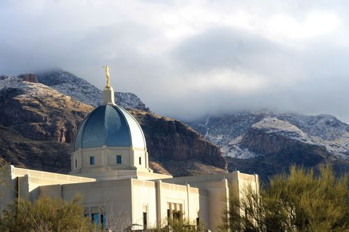 A photograph of the Tucson Arizona Temple with snow-dusted mountains in the distance.