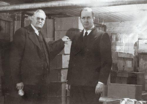 Ezra Taft Benson in Bergen, Norway.  Caption: "Inspecting welfare supplies with Pres. Petersen in mission office basement."    Collection Summary: Black-and-white views taken during Benson's February-December 1946 mission to postwar Europe to meet with Latter-day Saints, direct distribution of welfare supplies, and arrange for resumption of missionary work.