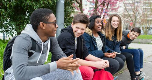 A group of young men and young women enjoy each others’ company as they visit together in Paris France.