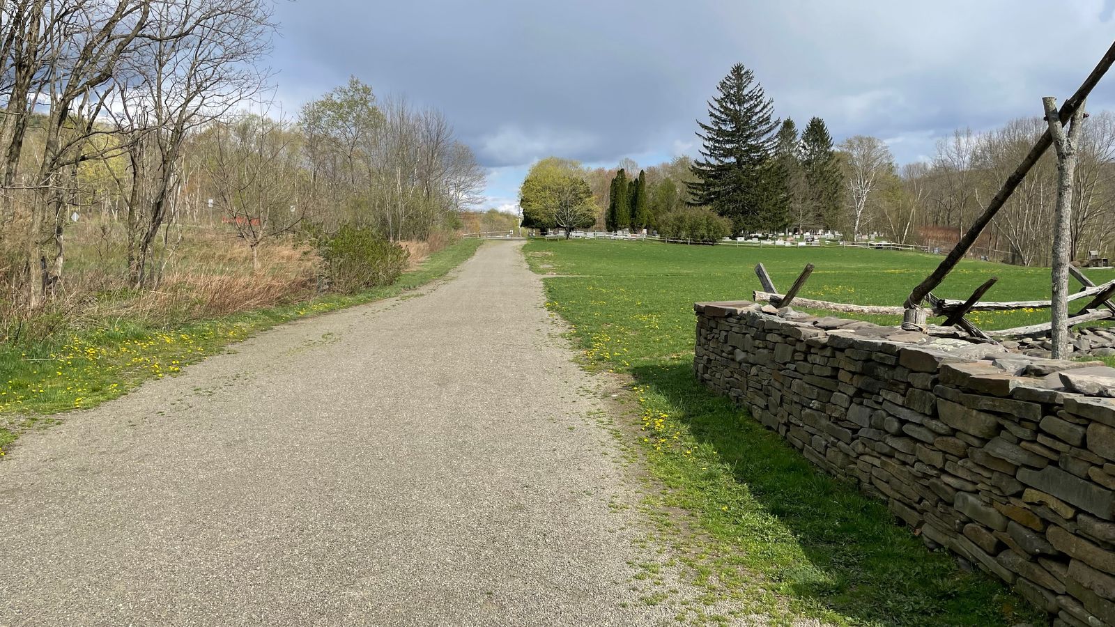 A gravel path that leads to a cemetery. 