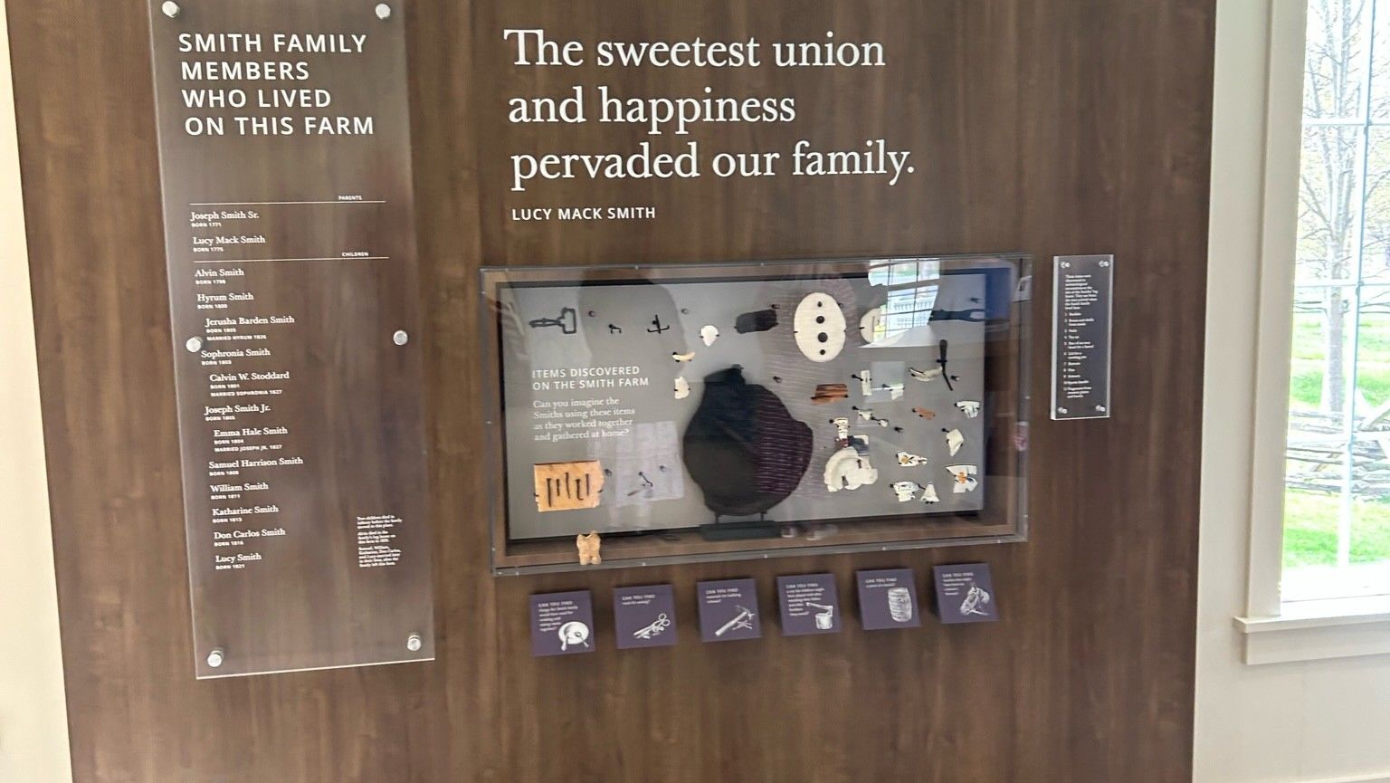 An exhibit wall featuring quotes and artifacts behind glass in a shadow box that is embedded into the wall.