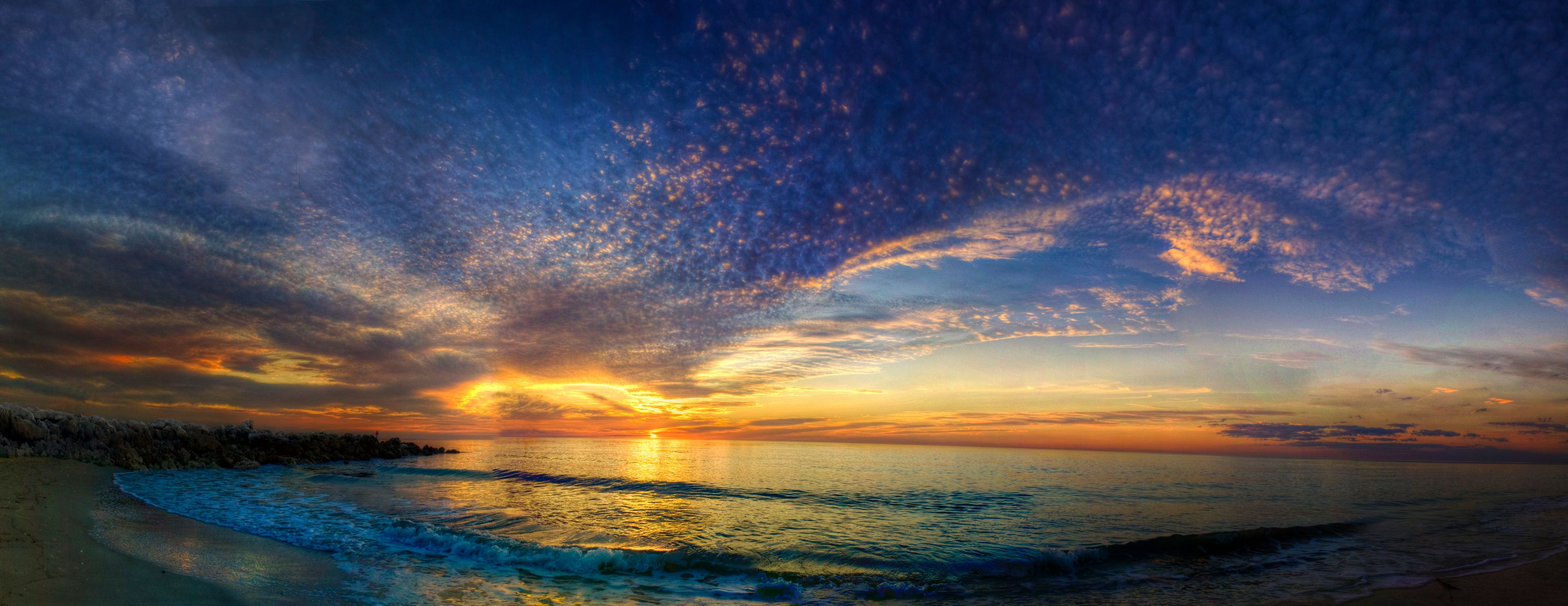 A panorama of the sun setting over the ocean.  