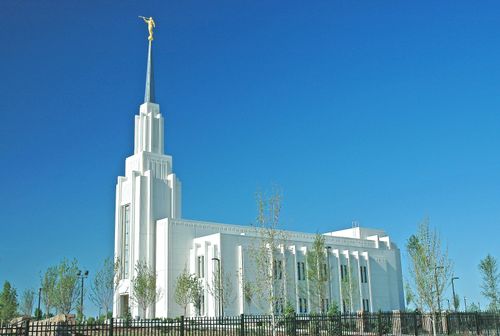 The side of the Twin Falls Idaho Temple during the day, with the fence and trees.