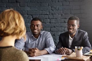 Two men interview a woman who has applied for a job at the company they work for.