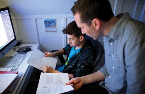 A father helps his son with his homework.