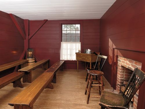 Narrow room with a fireplace and benches. Walls painted dark red.