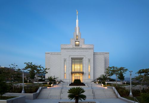 The entrance to the Tegucigalpa Honduras Temple in the evening, with stairs leading to the doors, lit up at night.