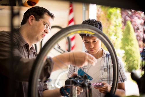 man teaching young man how to fix bicycle