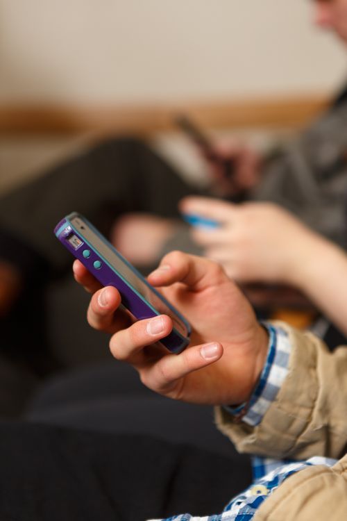 A young man is holding a purple smartphone next to others using smartphones.