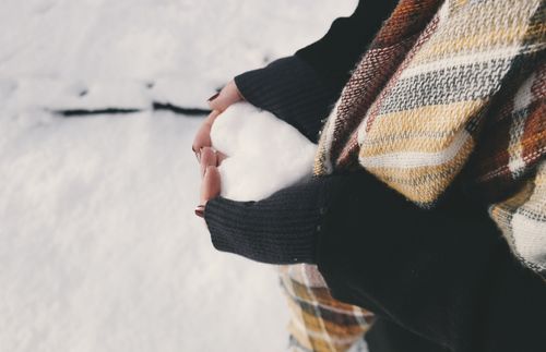 Hands holding a heart made of snow