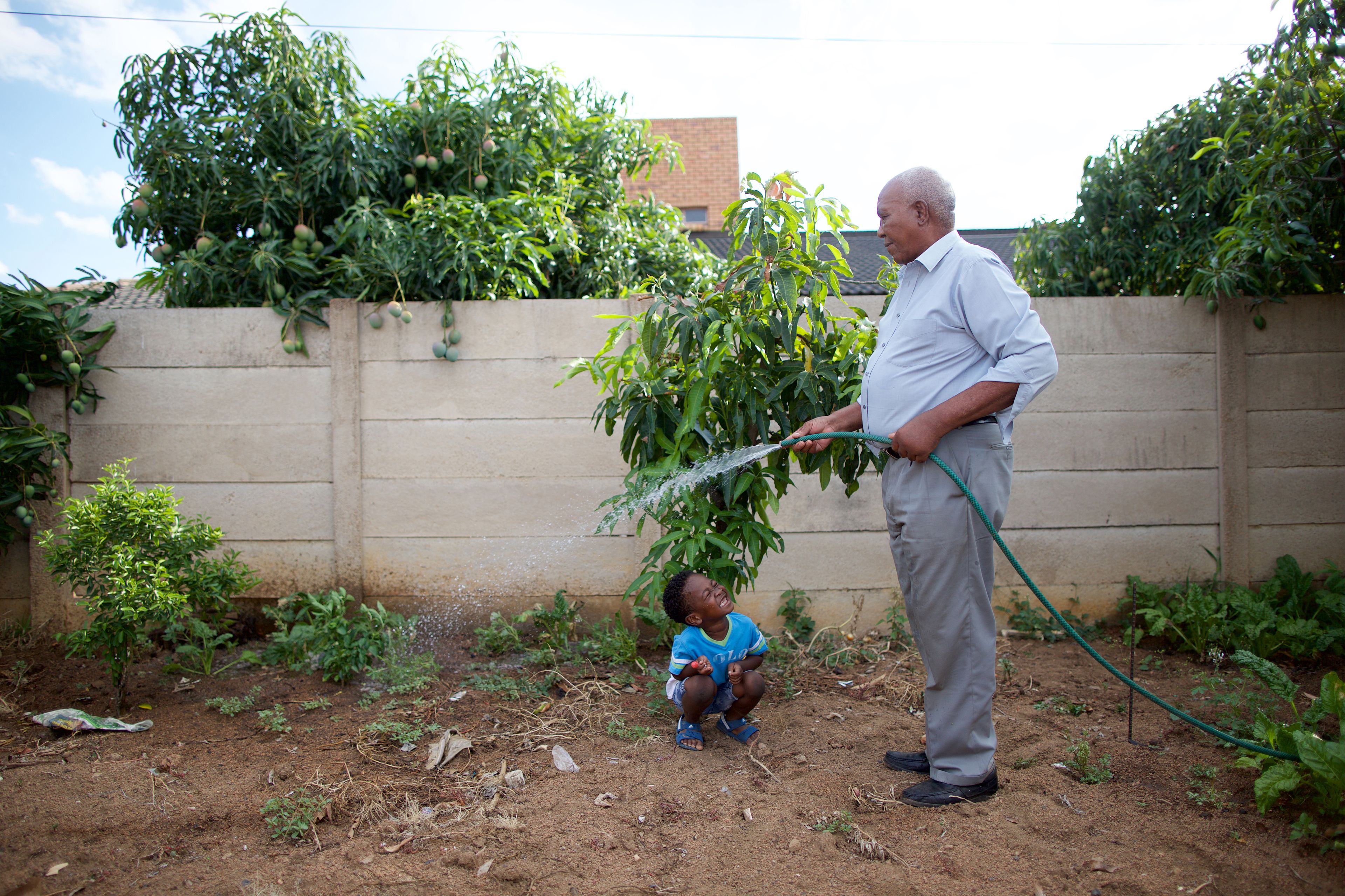 A grandfather and his grandson work and play together in their garden in South Africa.
