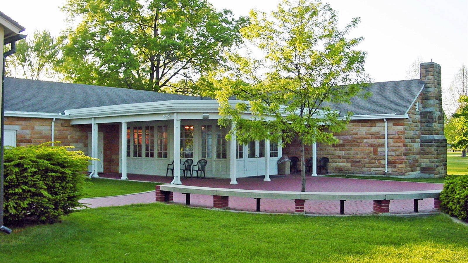 Single story stone building with walking path and benches in the foreground.