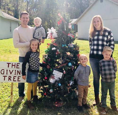 family standing by small Christmas tree outside