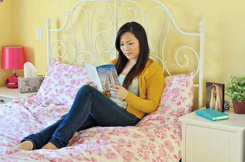 A young woman on a bed reading the For the Strength of Youth pamphlet.