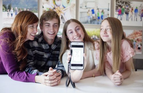 young woman holding up phone as others look on