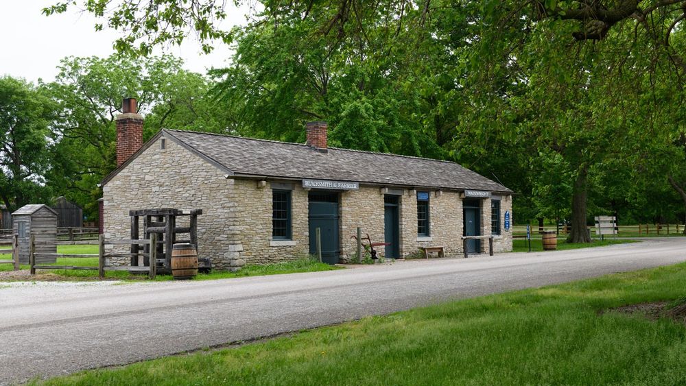 A long, single-story stone structure with multiple entries along an asphalt road.