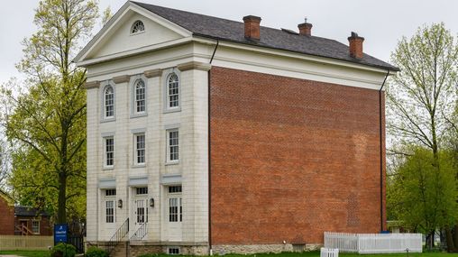 Three-story building with red brick on the side and white stone on the front façade.