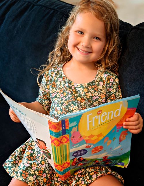 Svea Olson smiles as she reads the Friend Magazine.