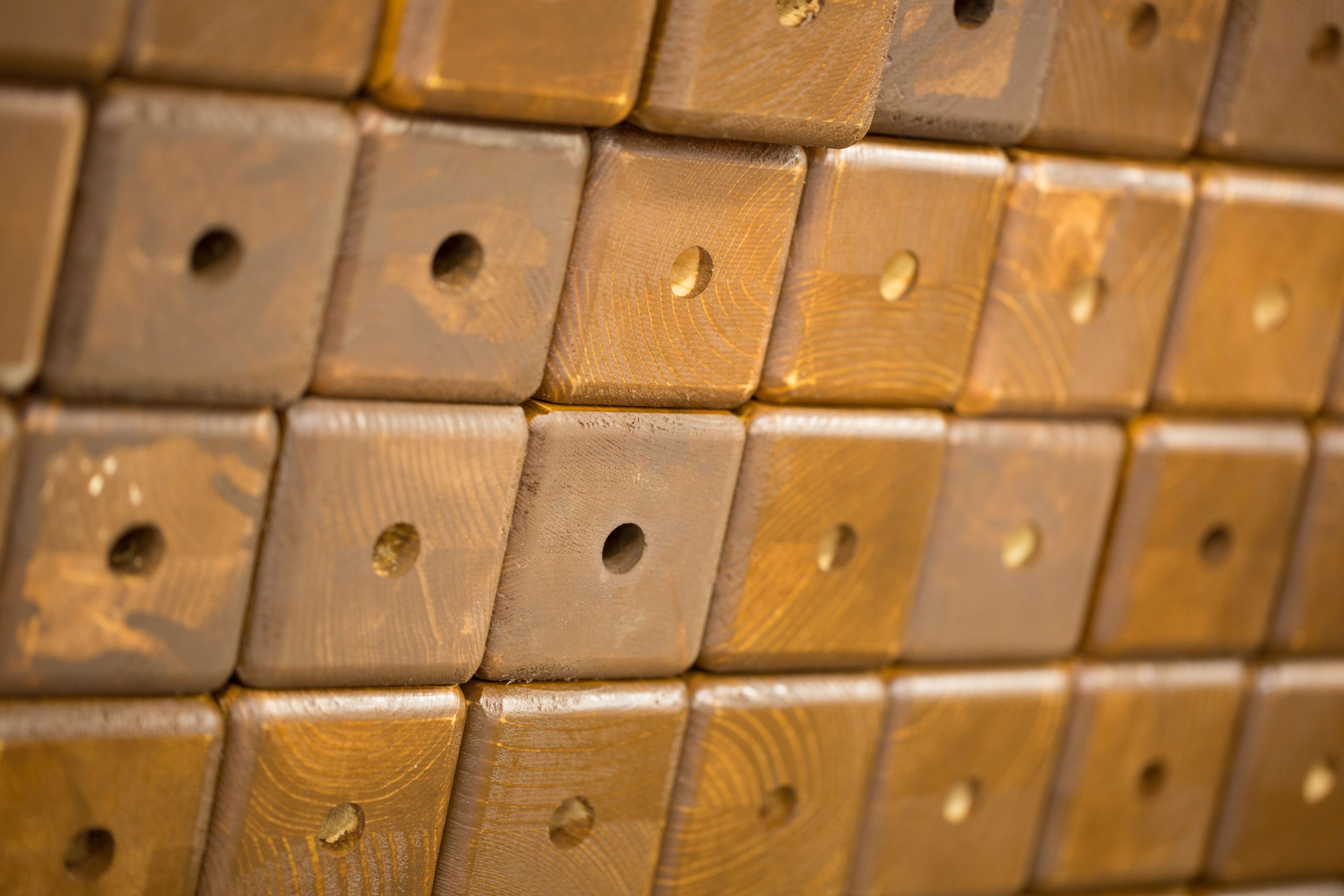 Pieces of wood with holes drilled into them, stacked close together.