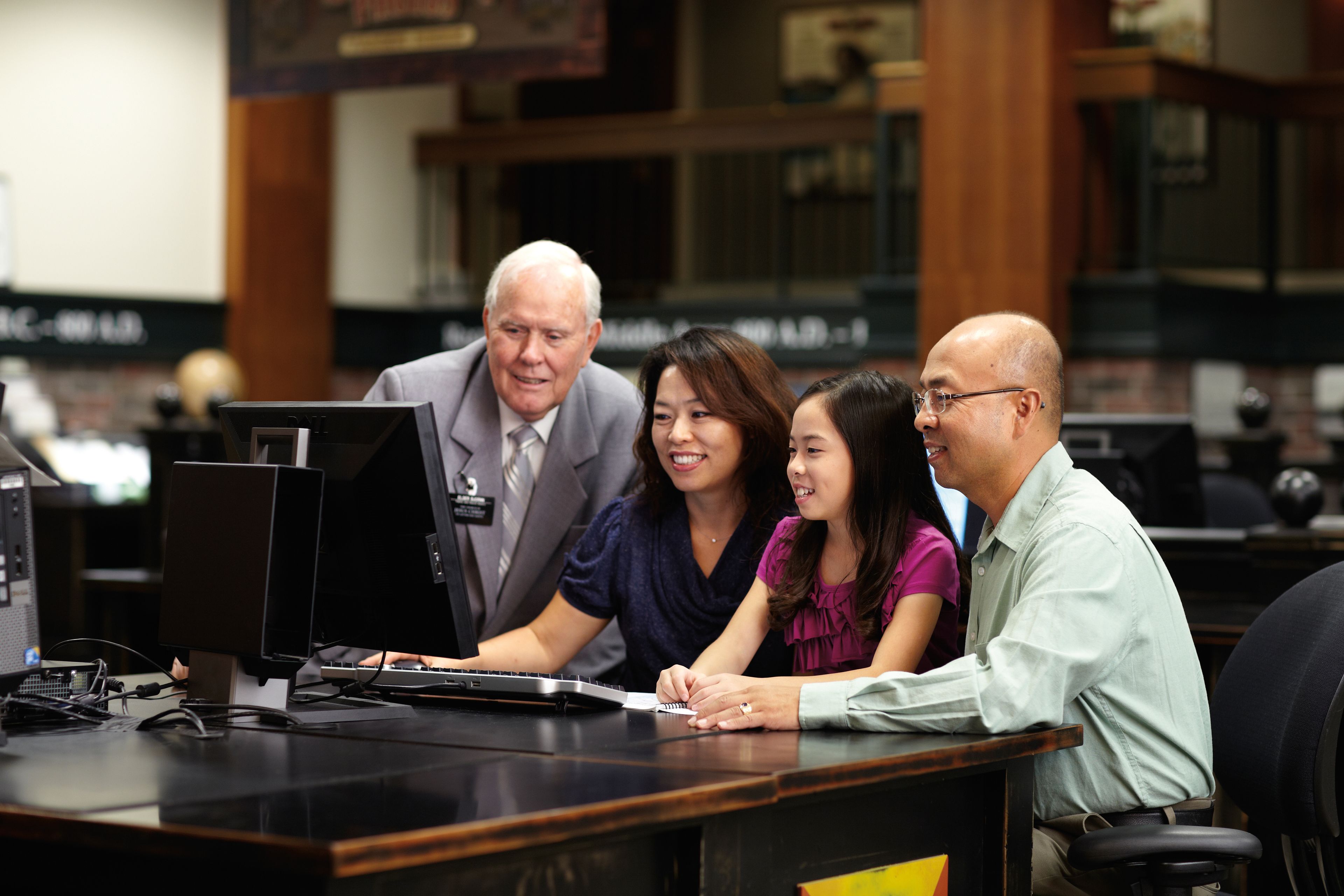 A senior elder missionary assists a couple in family history research at the Family History Library in Salt Lake City.