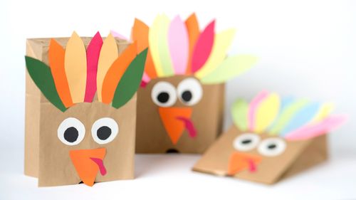 Three paper bags that have been decorated with colored paper to look like turkeys.